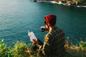person reading a book on a mountain
